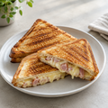 Illustrative square menu photo of golden toasted sandwich triangles with melted cheese, ham, and onion