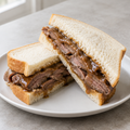 Illustrative square menu photo of a roast beef and gravy sandwich on soft bread